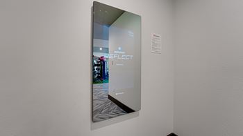 A mirror with a reflection of a room and a sign that says "REFLECT".